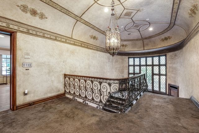 staircase featuring crown molding, carpet floors, and an inviting chandelier