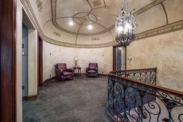 hallway featuring a notable chandelier, carpet, and vaulted ceiling