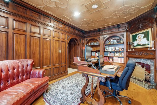 home office featuring crown molding, wood walls, light hardwood / wood-style floors, and built in shelves