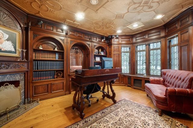 home office featuring a premium fireplace, built in shelves, crown molding, and light hardwood / wood-style flooring