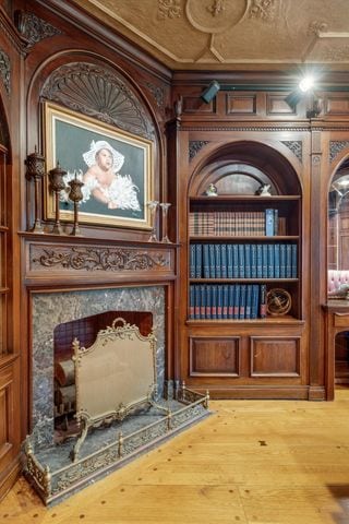 living area with hardwood / wood-style floors, built in shelves, and a premium fireplace