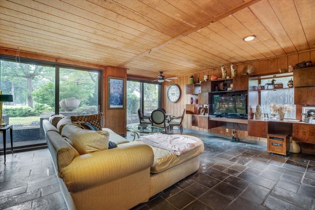 living room featuring ceiling fan, wooden ceiling, and wooden walls