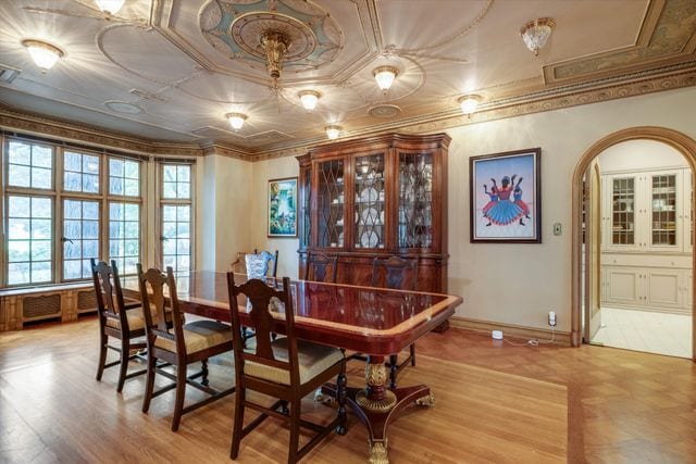 dining space with ornamental molding and light hardwood / wood-style flooring