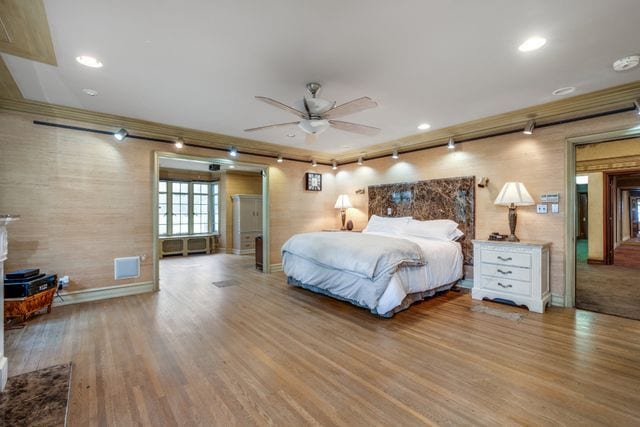 bedroom with ornamental molding, wood-type flooring, and rail lighting