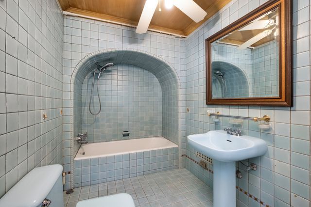 bathroom featuring toilet and tile walls