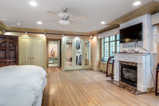 bedroom with crown molding, a high end fireplace, and light hardwood / wood-style flooring