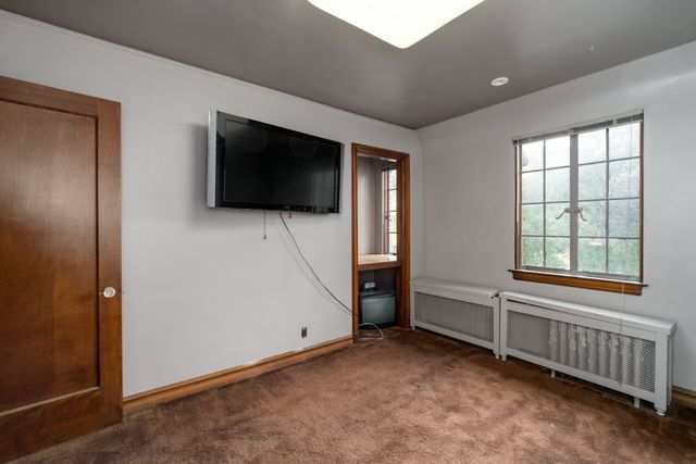 unfurnished bedroom with carpet and radiator heating unit