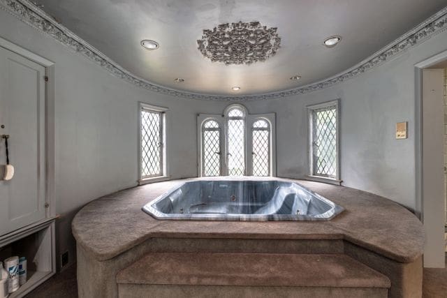 bathroom with a jetted tub and ornamental molding