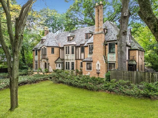 rear view of property with a high end roof, a lawn, and a chimney