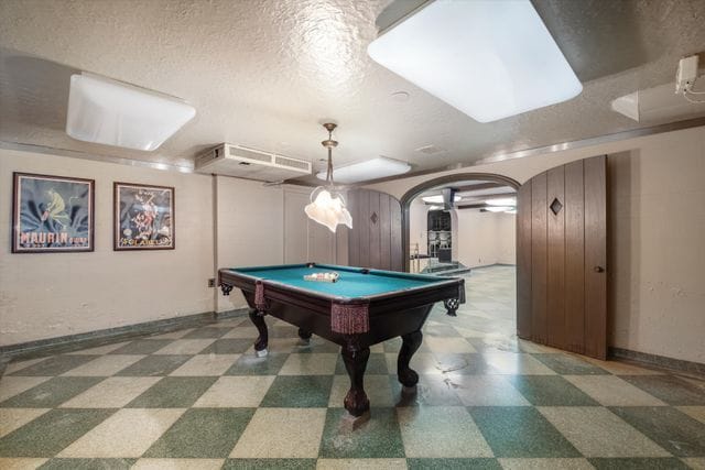 playroom featuring tile patterned floors, arched walkways, a textured ceiling, and pool table