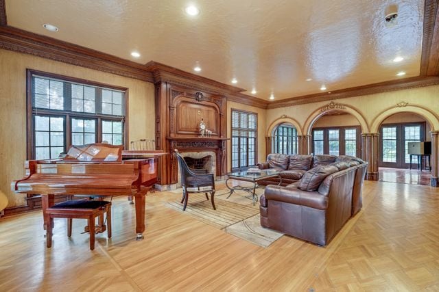 living area with a fireplace, a textured ceiling, crown molding, and french doors