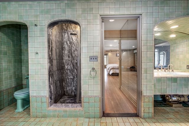 bathroom with tile walls, tile patterned floors, and toilet