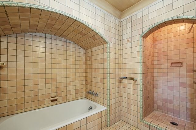 bathroom with tiled shower and tile walls