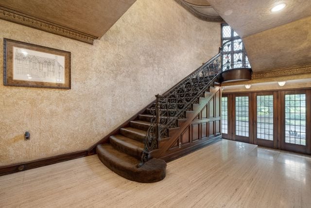 stairway featuring french doors, a towering ceiling, and wood-type flooring