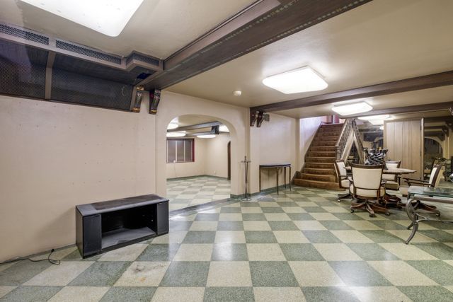 finished basement with stairs, tile patterned floors, and arched walkways