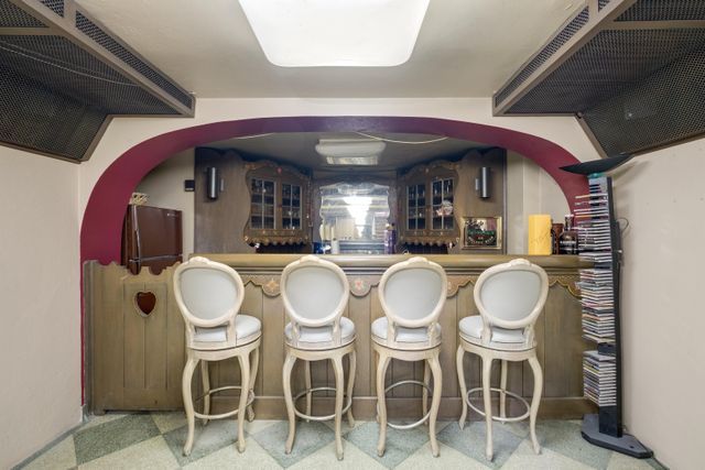 bar featuring a bar, freestanding refrigerator, exhaust hood, and under cabinet range hood