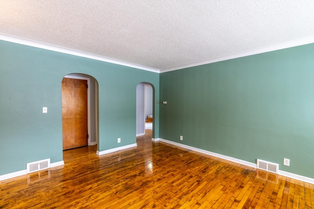 empty room featuring dark wood-type flooring, crown molding, and a textured ceiling