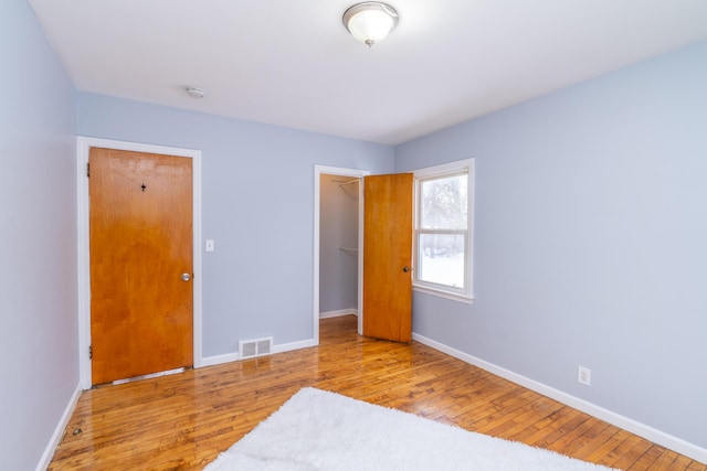 unfurnished bedroom featuring a spacious closet, light hardwood / wood-style flooring, and a closet