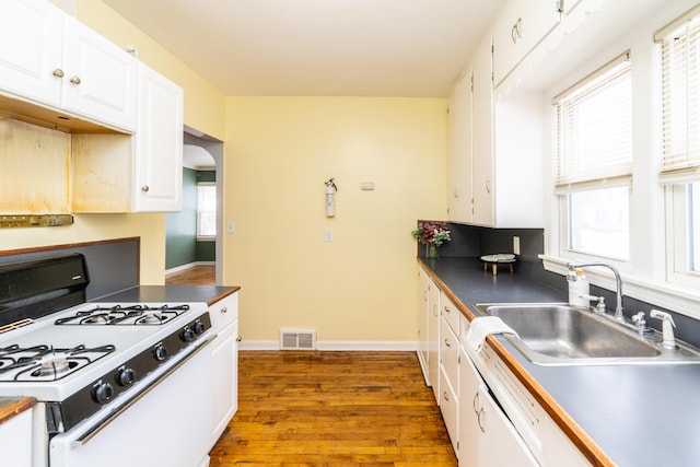 kitchen with sink, white cabinetry, dark hardwood / wood-style floors, a healthy amount of sunlight, and white gas stove