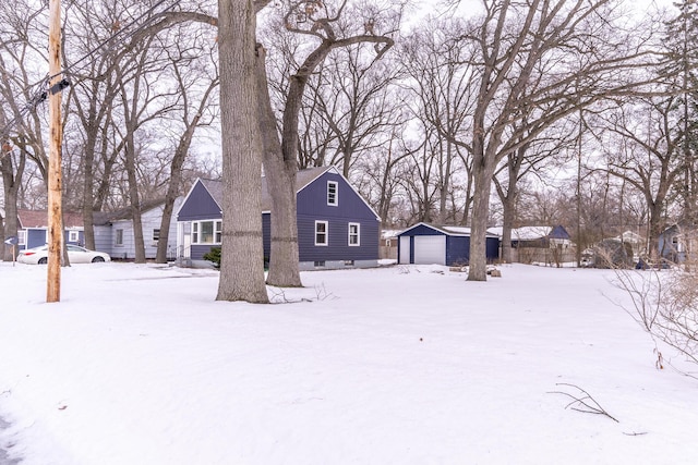 snowy yard featuring a garage and an outbuilding