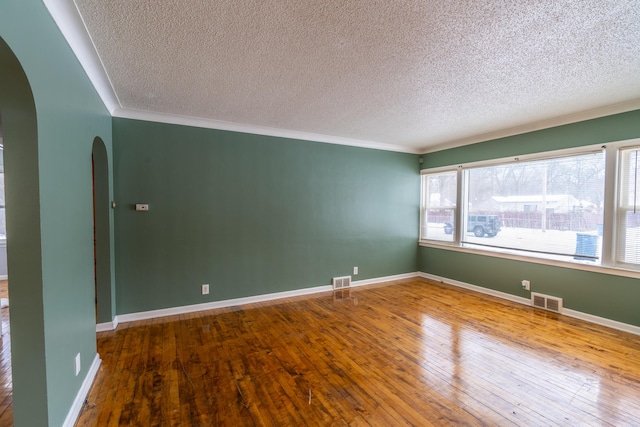 unfurnished room with wood-type flooring, a textured ceiling, and crown molding