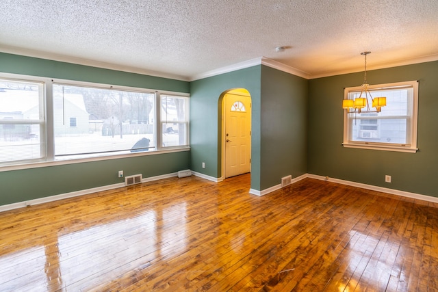 empty room featuring ornamental molding, wood-type flooring, a chandelier, and a textured ceiling