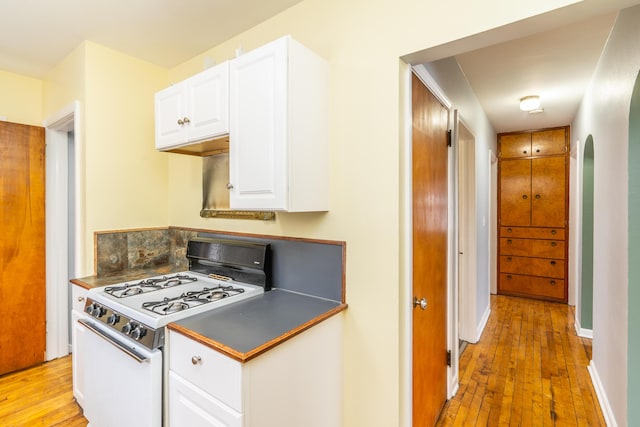 kitchen with light wood-type flooring, white range with gas stovetop, and white cabinets