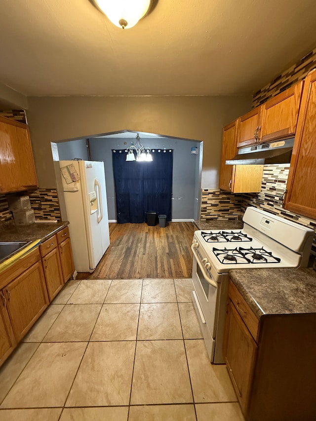 kitchen with sink, backsplash, light tile patterned floors, a notable chandelier, and white appliances