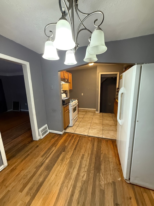 kitchen with white appliances, light hardwood / wood-style flooring, and a textured ceiling