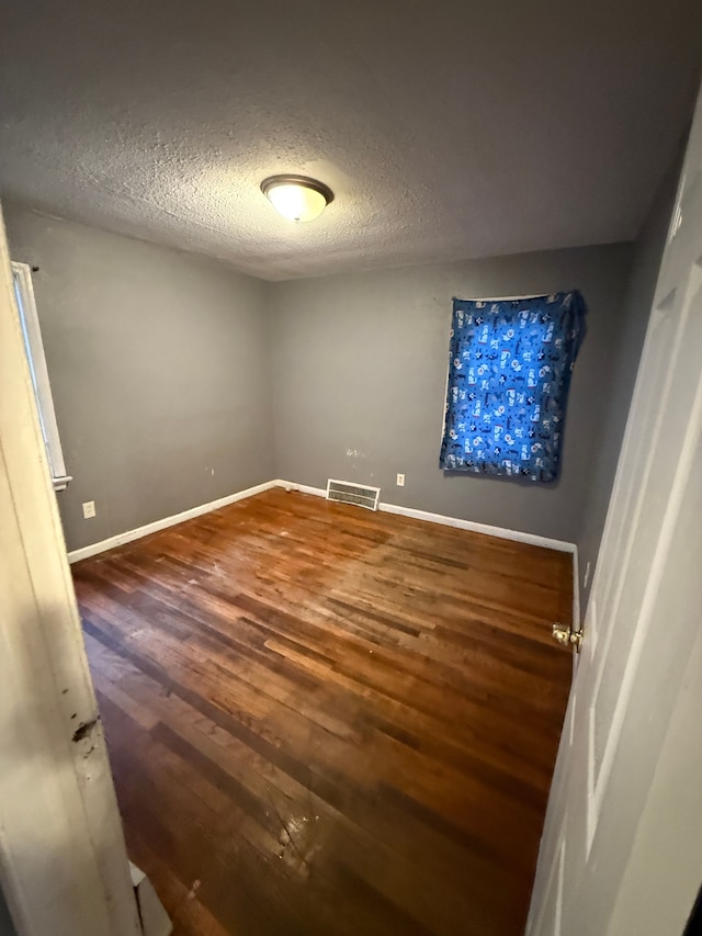 spare room with dark wood-type flooring and a textured ceiling