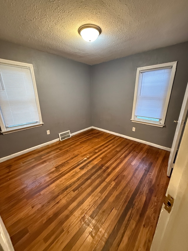 unfurnished room featuring a textured ceiling and dark hardwood / wood-style flooring