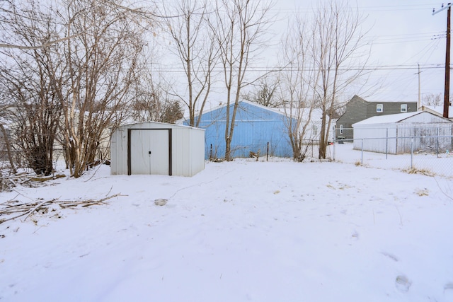 snowy yard featuring a storage unit