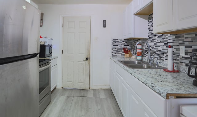 kitchen with sink, appliances with stainless steel finishes, light stone countertops, decorative backsplash, and white cabinets