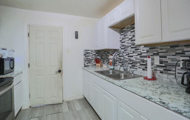 kitchen with sink, backsplash, white cabinets, electric range, and light stone countertops