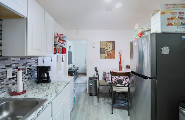 kitchen featuring white cabinetry, tasteful backsplash, and stainless steel refrigerator