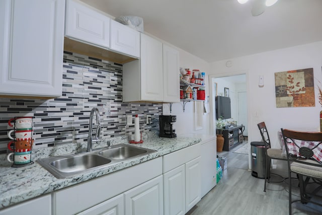 kitchen with light stone countertops, sink, white cabinets, and backsplash