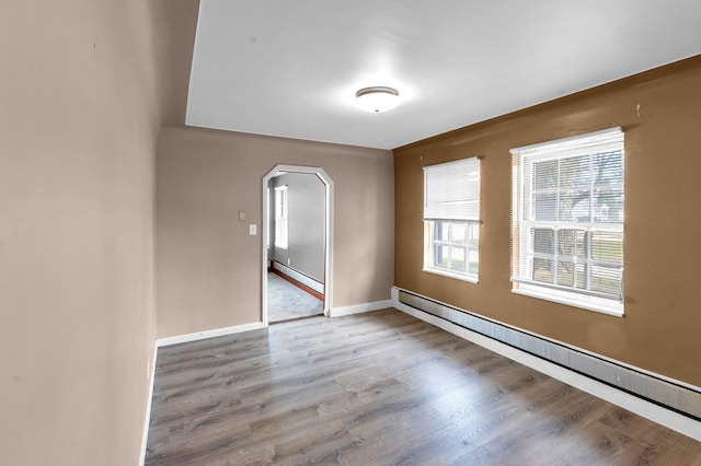 22810 E 13 Mile Rd, Saint Clair Shores, MI 48082 - unfurnished room featuring a baseboard heating unit, arched walkways, wood finished floors, and baseboards