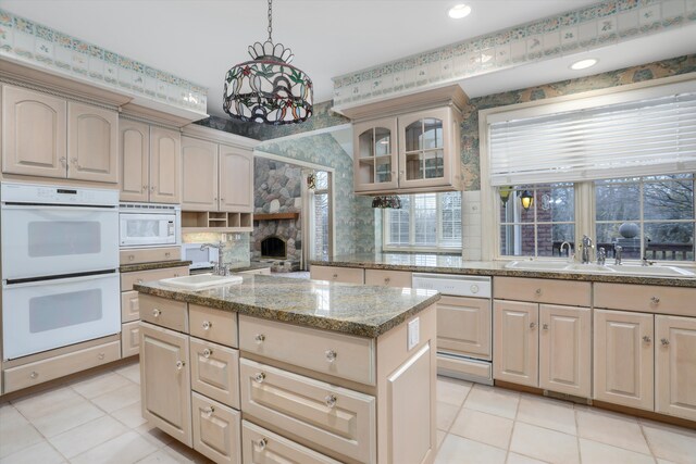 kitchen with white appliances, a center island, a healthy amount of sunlight, and a sink