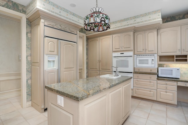 kitchen with a sink, a kitchen island, white appliances, wallpapered walls, and light stone countertops