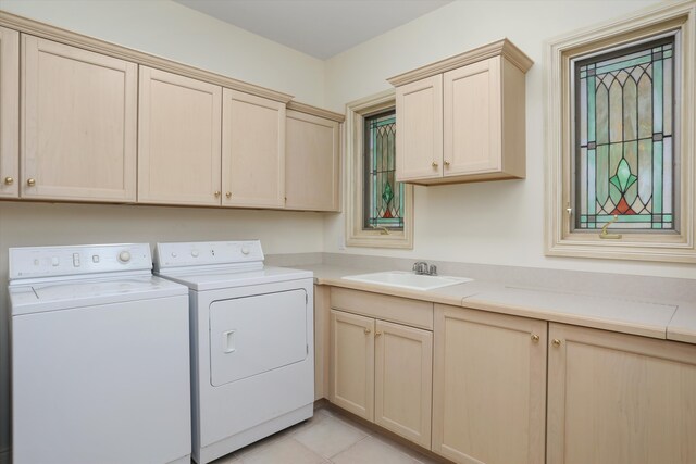 washroom with light tile patterned floors, cabinet space, washer and dryer, and a sink