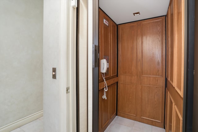 hallway with elevator and light tile patterned floors