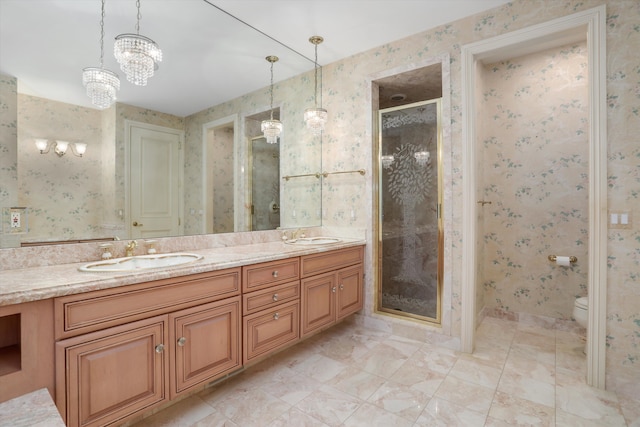 bathroom with double vanity, a stall shower, wallpapered walls, and a sink