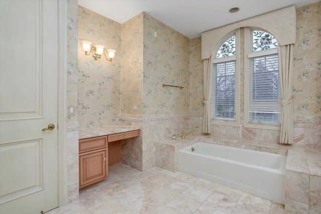 bathroom with wallpapered walls, tile walls, a bath, and vanity