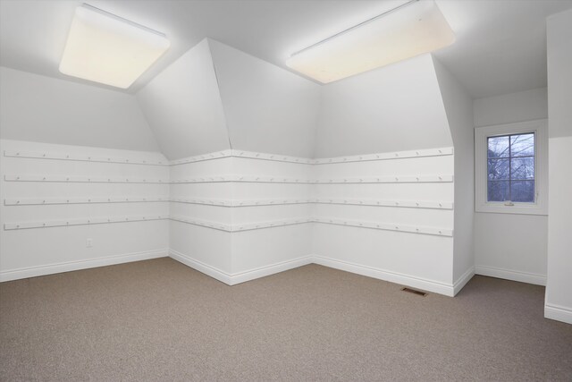 additional living space with carpet flooring, baseboards, visible vents, and vaulted ceiling