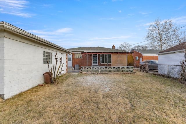 rear view of property with central AC unit and a lawn