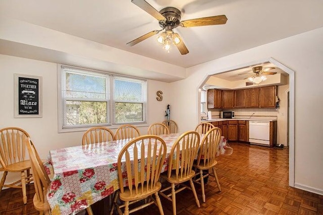 dining area featuring dark parquet flooring, sink, and ceiling fan