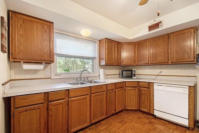 kitchen featuring tasteful backsplash, sink, ceiling fan, white dishwasher, and light parquet flooring