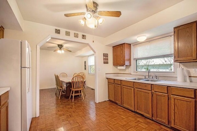 kitchen featuring white refrigerator, a healthy amount of sunlight, sink, and light parquet floors