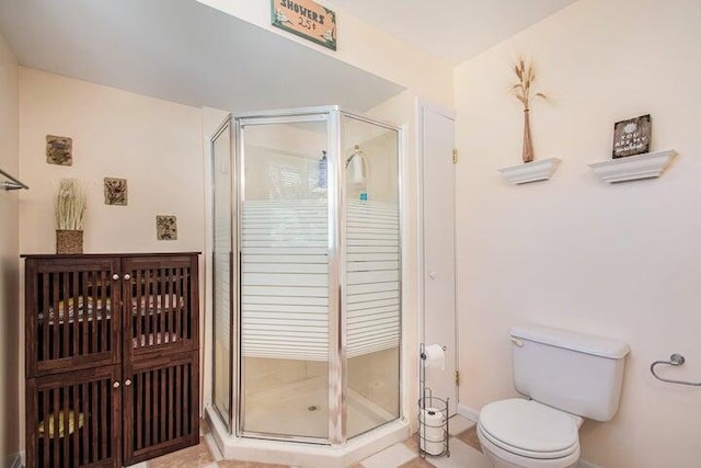 bathroom featuring a shower with door and toilet