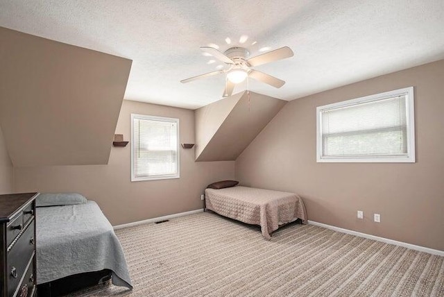 bedroom with multiple windows, carpet floors, a textured ceiling, and vaulted ceiling